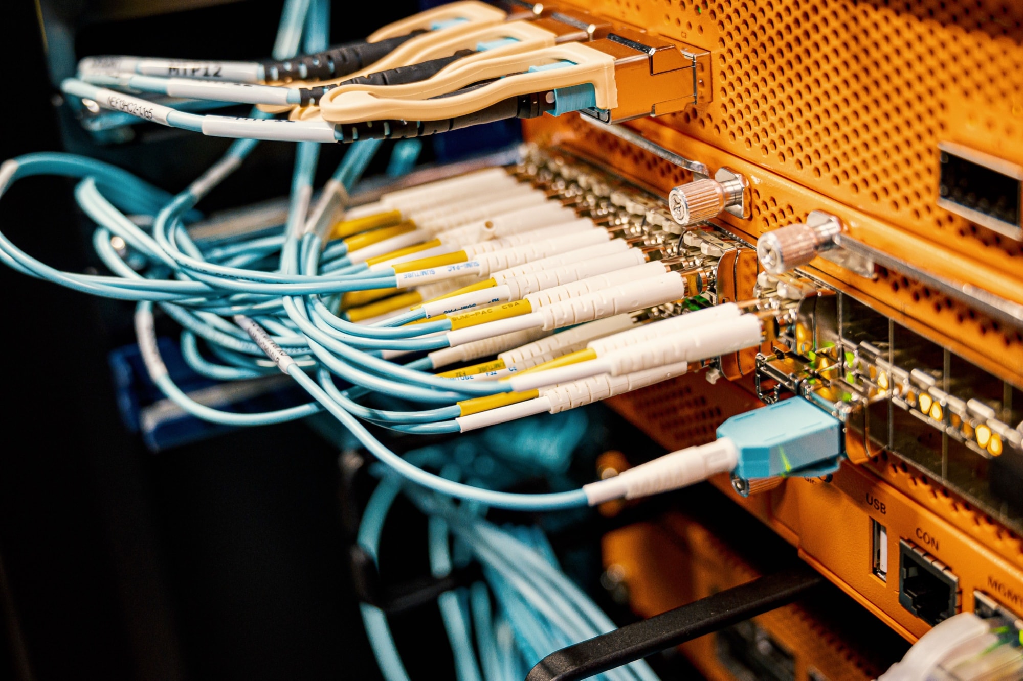 Fibre patch panel in the AfWS facility, aqua and white optical cables terminated into an orange line card.